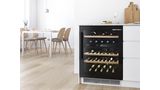 Der Weink&uuml;hlschrank mit Glast&uuml;r von Bosch l&auml;sst den Blick frei auf die Weinsammlung. Moderner, lichtdurchfluteter Essbereich links.