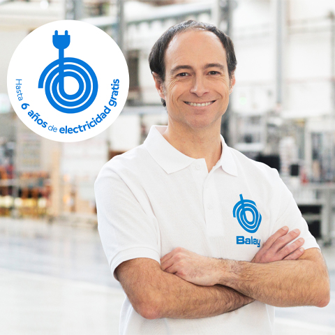Hombre sonriente con polo Balay en f&aacute;brica, junto a un logo de enchufe que anuncia "Hasta 6 a&ntilde;os de electricidad gratis".