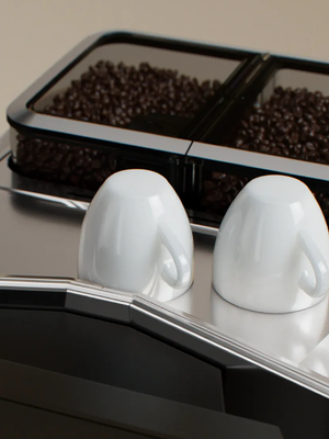 Kaffeevollautmat mit Detailausschnitt Ger&auml;teoberseite mit Doppeltem Bohnenbeh&auml;lter und zwei Espresso-Tassen im Vordergrund