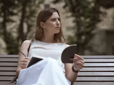 Woman sitting on a bench with a note pade and pen