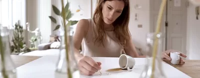 A women holding coffee cup and drawing with coffee