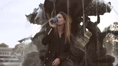 Woman sitiing with a cup of coffee at a fountain