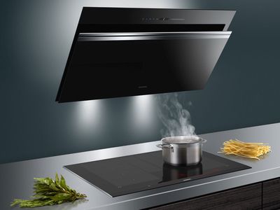 Elegancki czarny okap nad płytą indukcyjną z parującym garnkiem i świeżymi ziołami