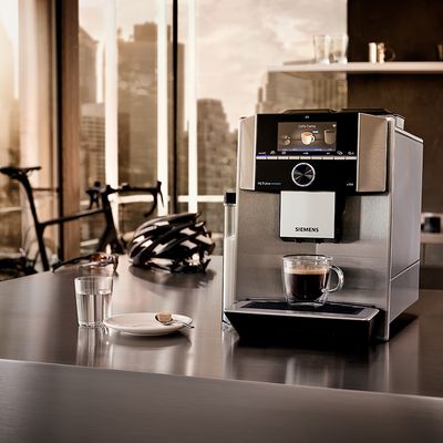 Culture café Siemens - Une machine à café tout automatique EQ.9 Siemens sur une table, un vélo en arrière plan.