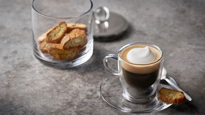 En espresso med krämigt skummad mjölk och biscottis. 