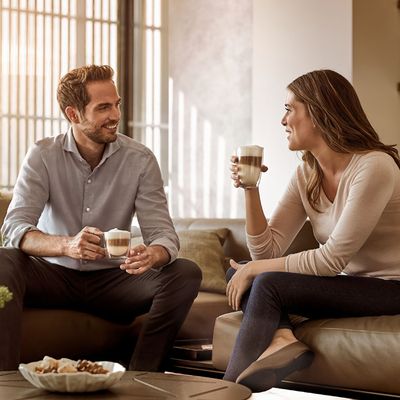 Siemens: To personer sitter i en sofa og drikker kaffe og prater