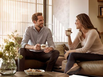 Siemens : un homme et une femme boivent du café sur un canapé et discutent