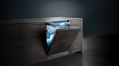 Cucina moderna con ante in legno scuro e lavastoviglie da incasso Siemens semiaperta con interno illuminato da luce blu