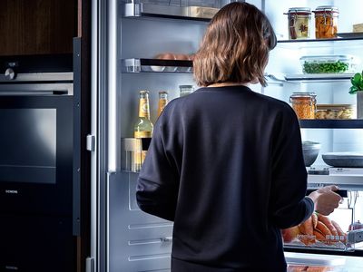 Siemens: eine Person stellt einen Behälter in den Kühlschrank