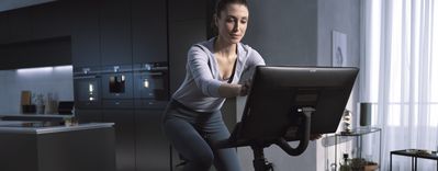 Smart kök: Kvinna styr smart ugn från motionscykel