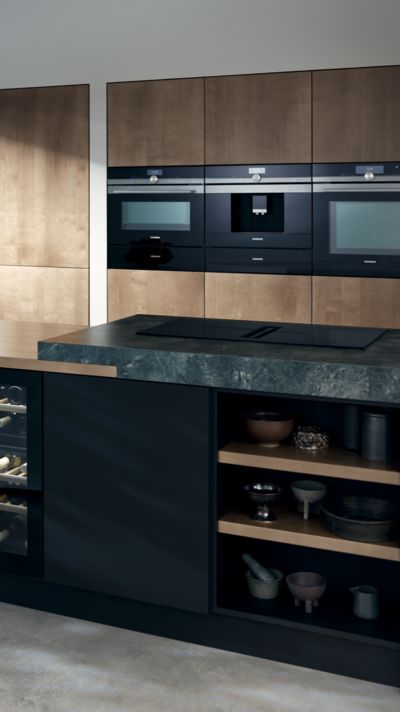 Cucina elegante aperta con frontali in legno e dotata di elettrodomestici Siemens.