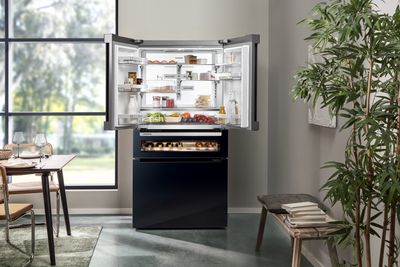 Moderni keittiö, jossa on musta multidoor-jääkaappi viininsäilytystilalla ja kaunis sommitelma kasveja ja maljakoita.