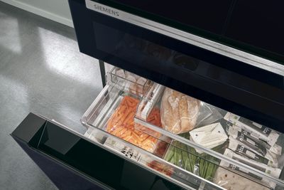 Siemens: persoon die met de Home Connect app de inhoud van de koelkast checkt