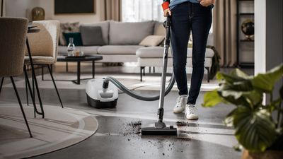 Eine Person befindet sich in einem modernen Wohnzimmer und saugt den Boden mit einem leistungsstarken Siemens Staubsauger.