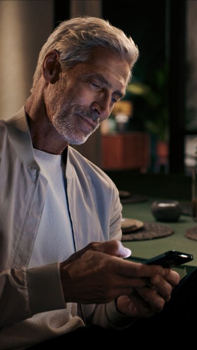 Ein Mann sitzt an einem Tisch und bedient sein Smartphone