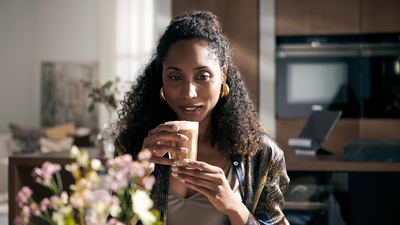Femme portant un verre de café à ses lèvres.