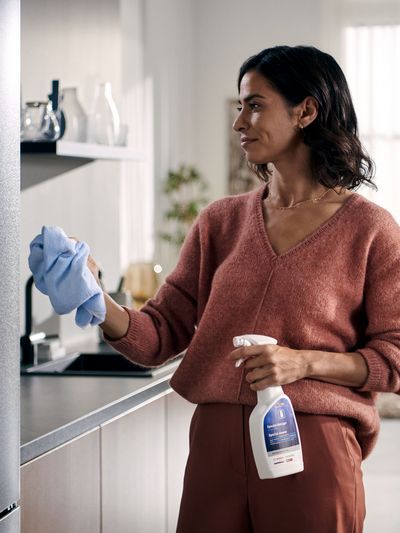 Eine Frau reinigt einen Siemens Kühlschrank mit Reinigungsprodukten von Siemens