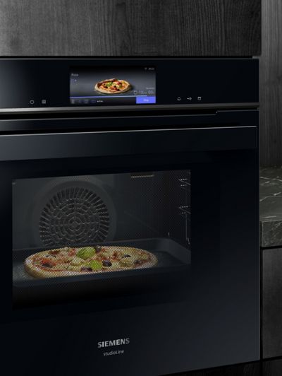 Smarta vitvaror i intelligent kök - bild på ugn som gräddar pizza