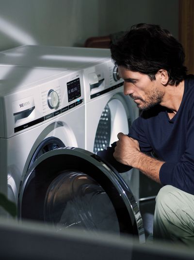 Smarta vitvaror – bild på man som lägger in tvätt i tvättmaskin