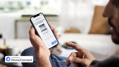 Bild tittar på mobiltelefon med Home Connect som visar status för smart diskmasking