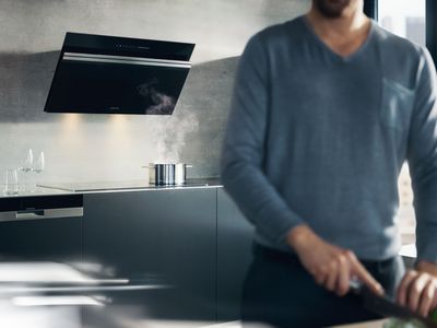 Smart köksfläkt: cookConnect - bild på någon som lagar mat vid spis med smart köksfläkt