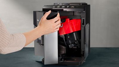 En åbner servicelågen foran på den fuldautomatiske espresso-/kaffemaskine EQ500. Maskinens indre ses.