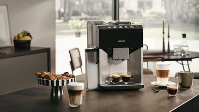 La machine EQ500 est placée sur un îlot de cuisine, avec différents cafés de spécialité versés dans des verres et des tasses disposés devant lui.