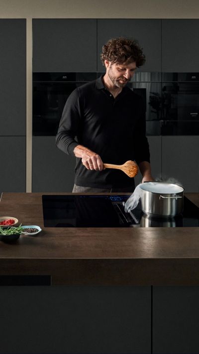 Un homme est en train de cuisiner avec une table de cuisson Siemens
