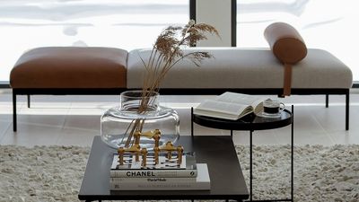 A coffee table with books and a vase on it, adding a touch of elegance to the living room decor.