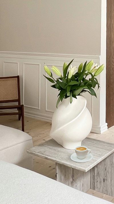 Vita liljor i vit vacker vas och en kaffekopp med perfekt kaffe i Rasmus Mallings hem