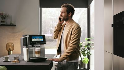 Person talking on a mobile phone whilst coffee machine makes drink in background