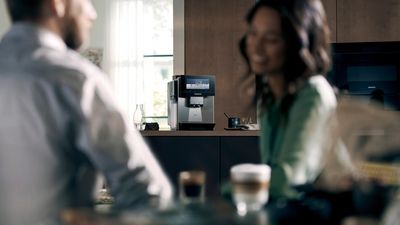 Cucina moderna con macchinetta del caff&egrave;, elettrodomestici e armadi in legno.