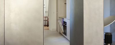 Cuisine moderne avec des murs gris élégants, des armoires minimalistes et une chaise confortable dans le salon adjacent.