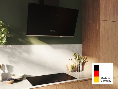 Eine Siemens Made in Germany Dunstabzugshaube über einem Kochfeld eingebaut in einer modernen Küchenzeile aus Holz.