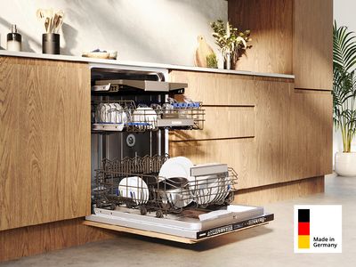 Ein befüllter Siemens Geschirrspüler Made in Germany mit geöffneter Tür, eingebaut in einer modernen Küchenzeile aus Holz.