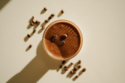 Bovenaanzicht van een glas met koffie-banaan-smoothy. Het is versierd met koffiebonen bovenop en rondom. Een heerlijk koffierecept.