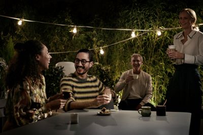 Przytulne spotkanie na świeżym powietrzu – cztery osoby dzielące się napojami i deserami wśród zieleni