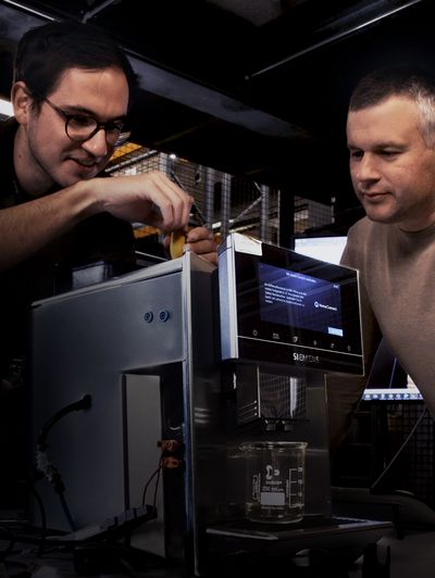 Two people looking down at the top of a Siemens coffee machine