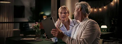 A man and woman are seated at a table, engaged with a tablet, sharing ideas and collaborating on a project.