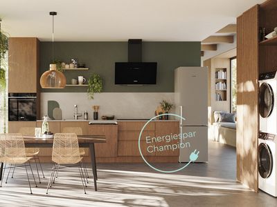 Eine moderne, helle Küche mit Holzfronten, die mit energieeffizienten Hausgeräten von Siemens ausgestattt ist. Auf dem Bild ist ein Störer mit dem Wort Energiespar-Champions abgebildet.