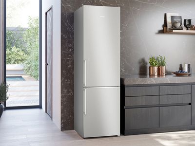 Eine helle, offene Küche, in der eine freistehende silberfarbene Siemens Kühl-Gefrier-Kombination steht.