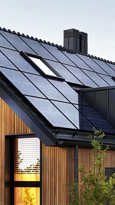 Beleuchtetes Haus mit Solarpanelen bei Dunkelheit