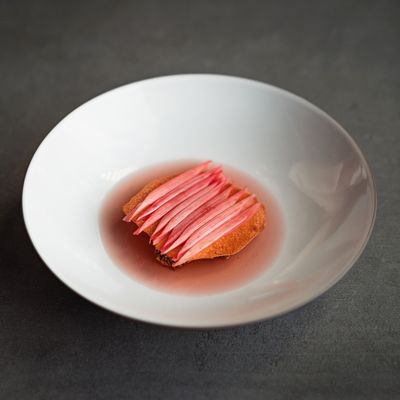 Une élégante table de cuisson à induction noire avec une poêle grésillante, libérant de la vapeur, à côté d'un bol de plat garni