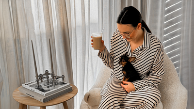 Laura koltukta, bir elinde kahvesi, kucağında küçük köpeğiyle oturuyor.