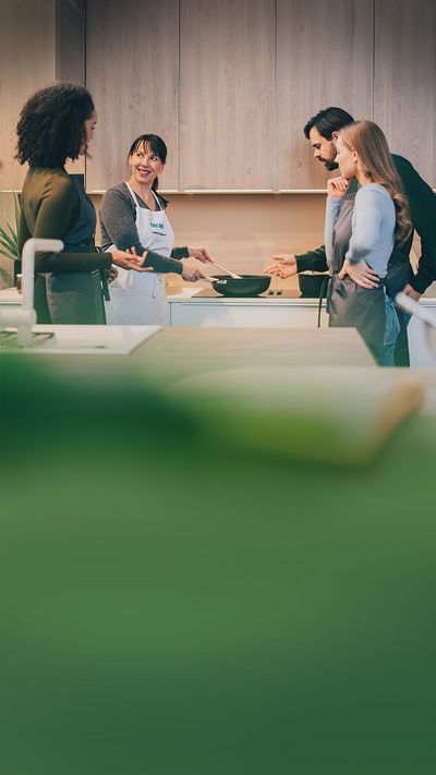 Vier Personen stehen gemeinsam vor einem Siemens Kochfeld und kochen zusammen.