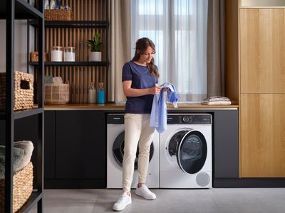 vrouw met overhemd in handen voor wasmachine en droger