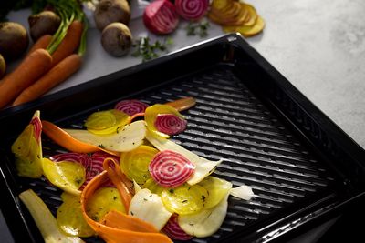 Detalle de una bandeja perforada airFry con verduras y hortalizas cortadas en rodajas finas 