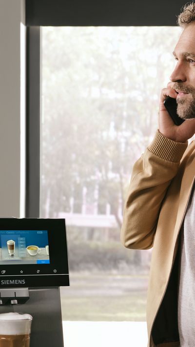 Siemens Coffeeworld - Žena telefonuje vedle plně automatického tichého kávovaru Siemens EQ.9