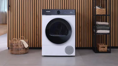 Moderne hvit tørketrommel i minimalistisk vaskerom med trelistvegg og oppbevaringskurver.