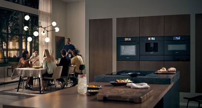 People drinking together with multiple Siemens appliances in kitchen